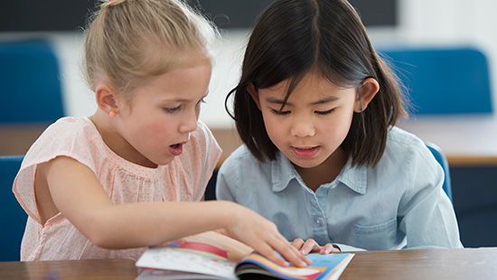 Children reading book at desk